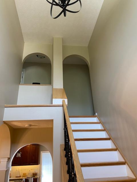 Two-story foyer with archways and a repainted staircase with wrought iron railing
